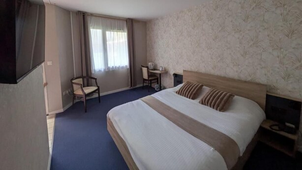Una habitación de hotel con una cama grande, un escritorio, una silla y un televisor.