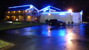 Un edificio con un coche estacionado al frente, iluminado por luces azules.