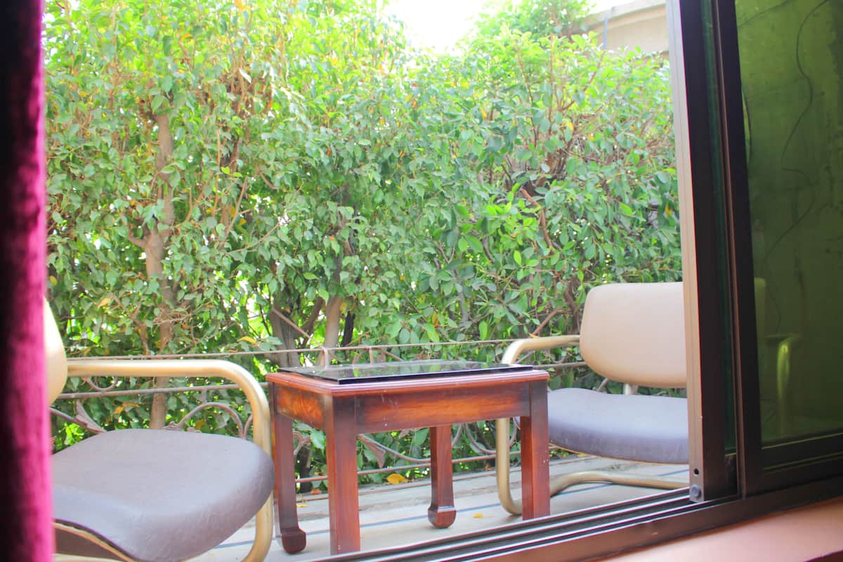 Un balcón con una mesa y dos sillas, con vistas a un jardín verde y exuberante.