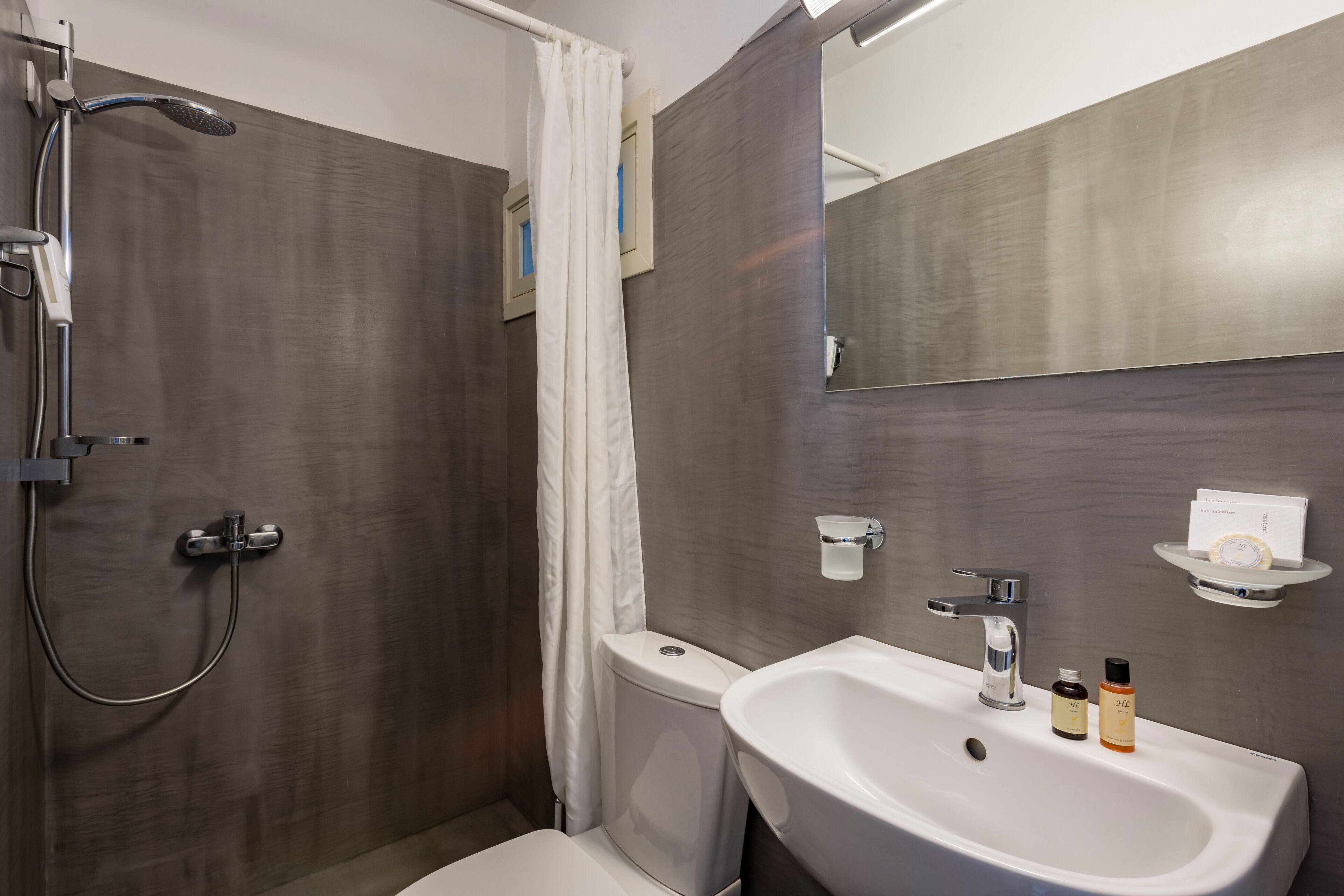 Een moderne badkamer met douche, toilet, wastafel en spiegel.