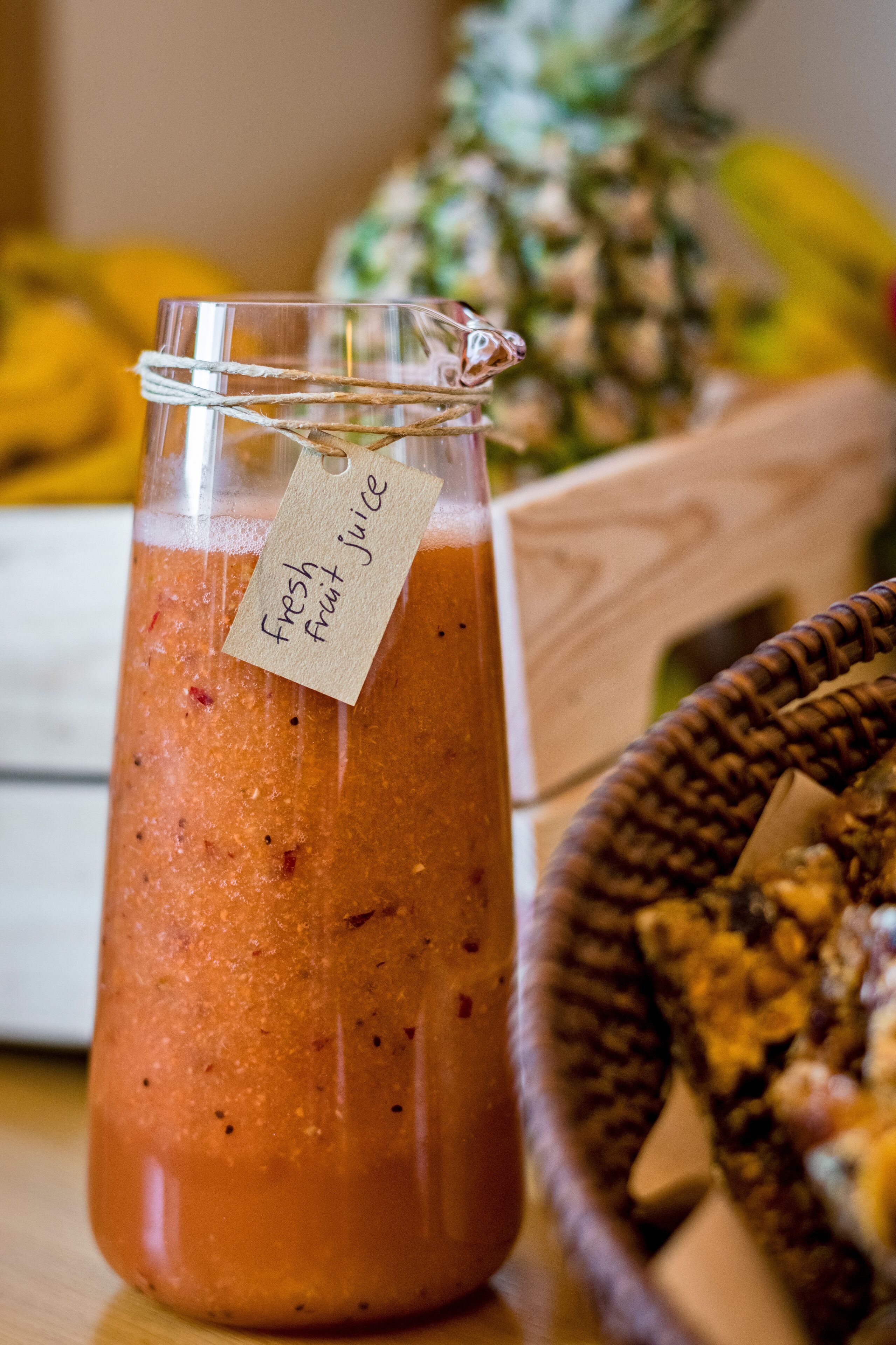 Un bocal en verre avec une étiquette indiquant « jus de fruits frais » posé sur une surface en bois.