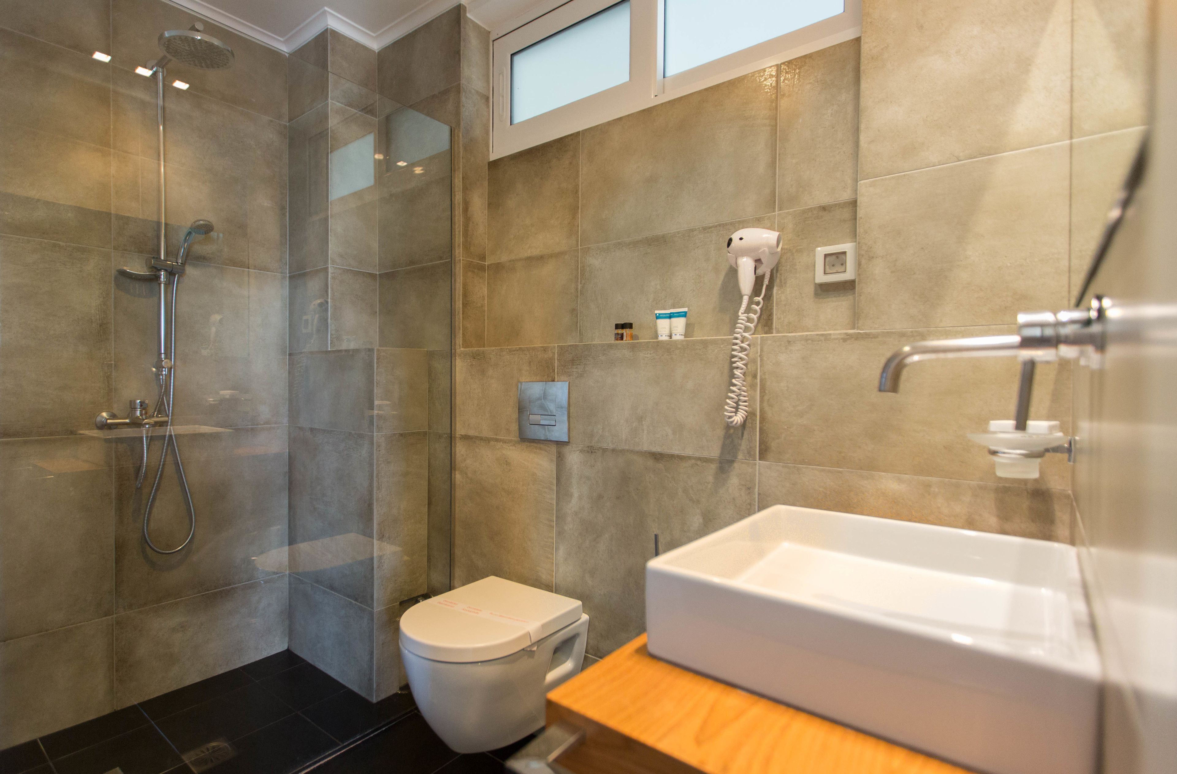 A modern bathroom with a glass-enclosed shower, a white toilet, and a large white sink.