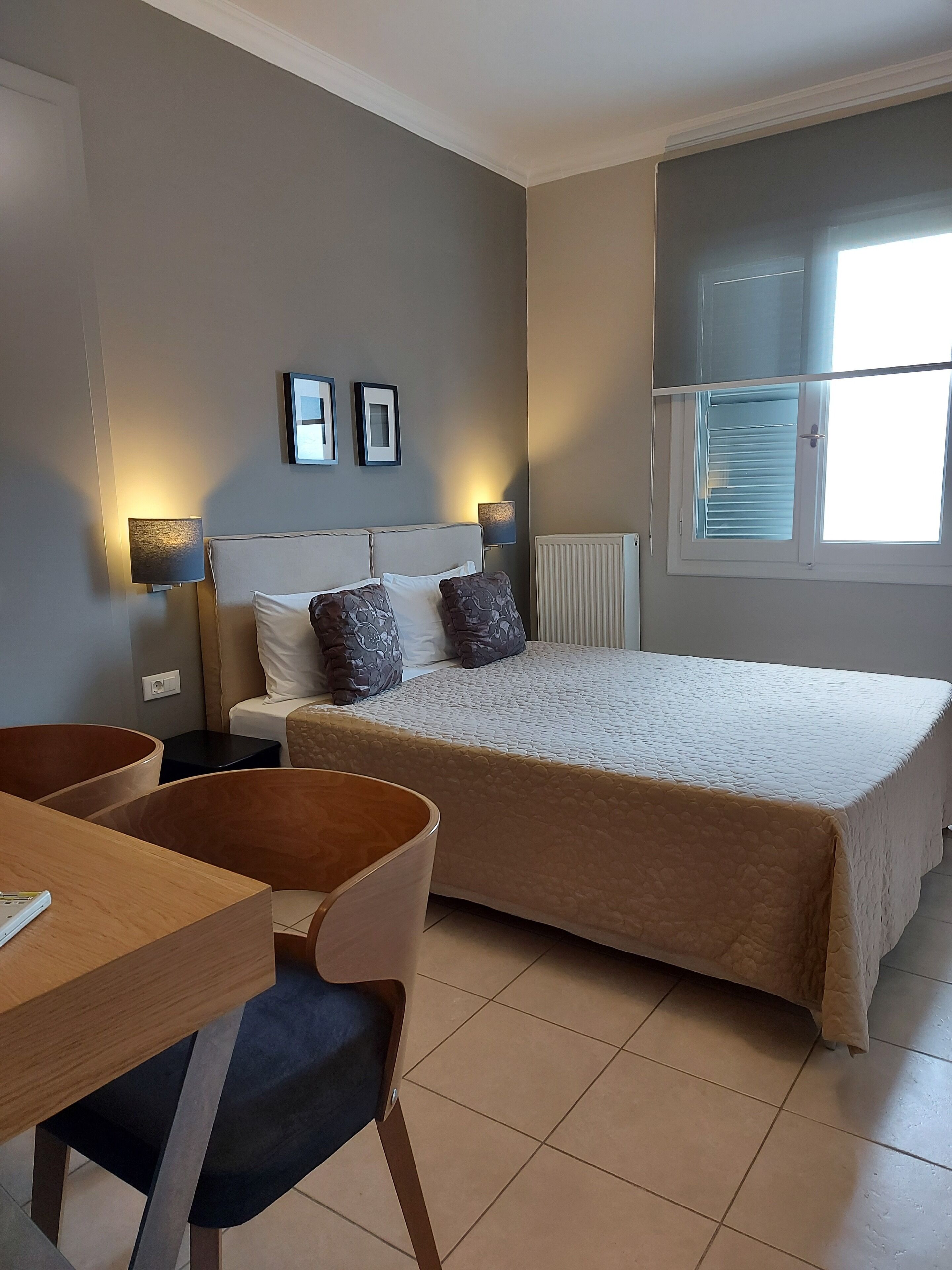 Un dormitorio con cama, mesitas de noche, un escritorio y sillas.