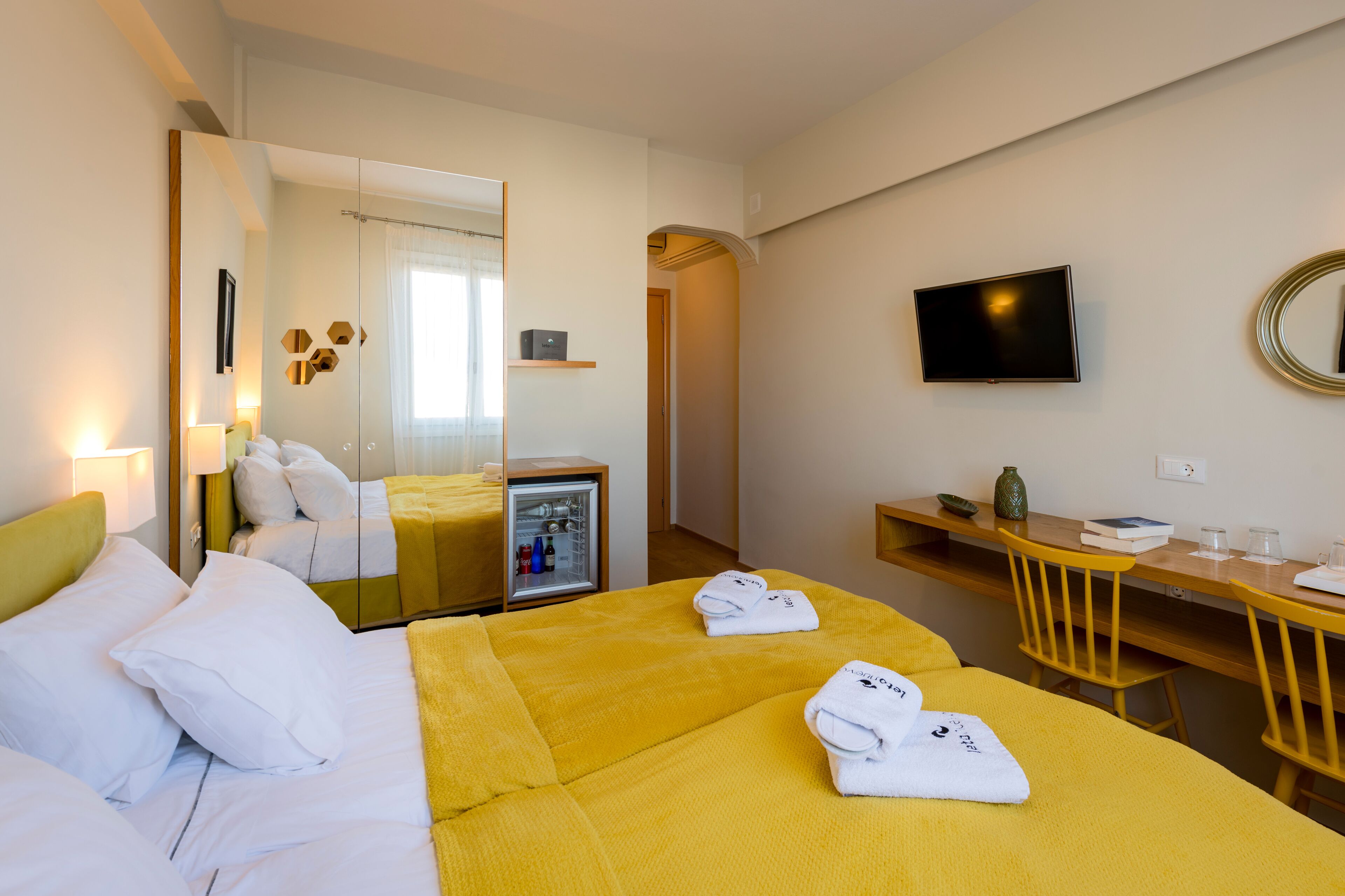 A hotel room with a bed, a desk, a TV, and a mirror.