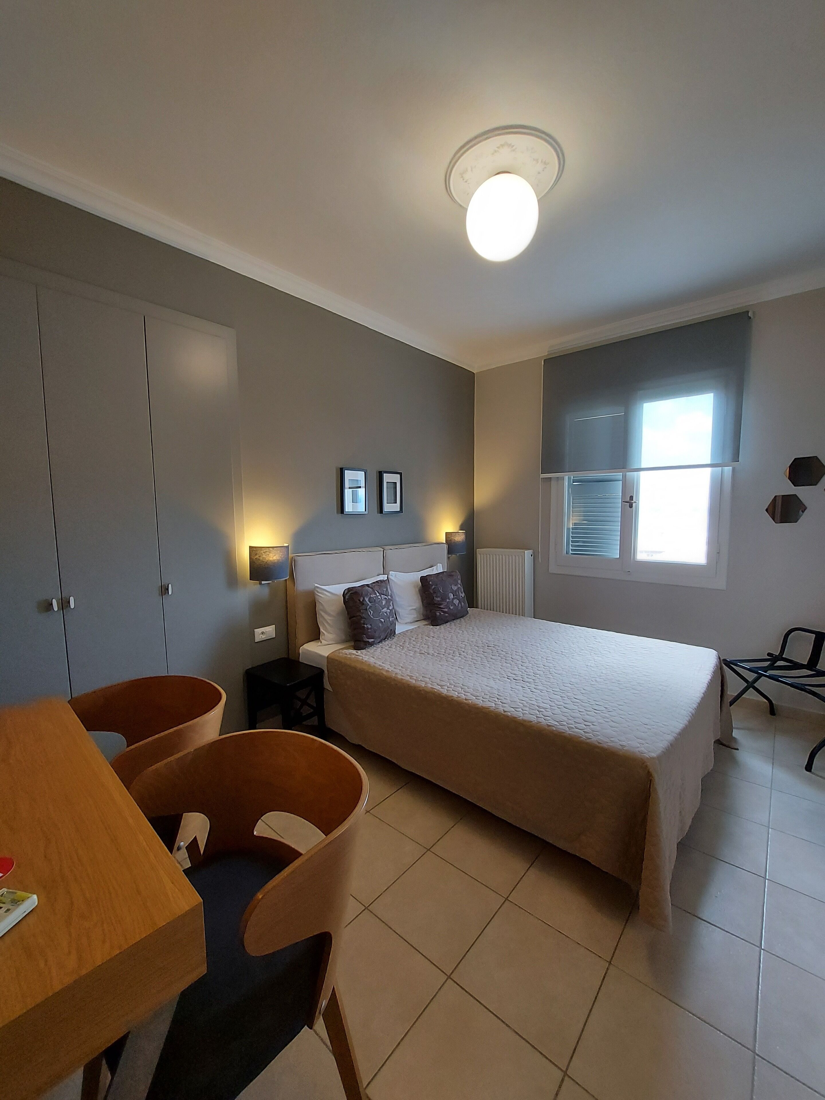 A bedroom with a bed, a desk, a chair, and a window.