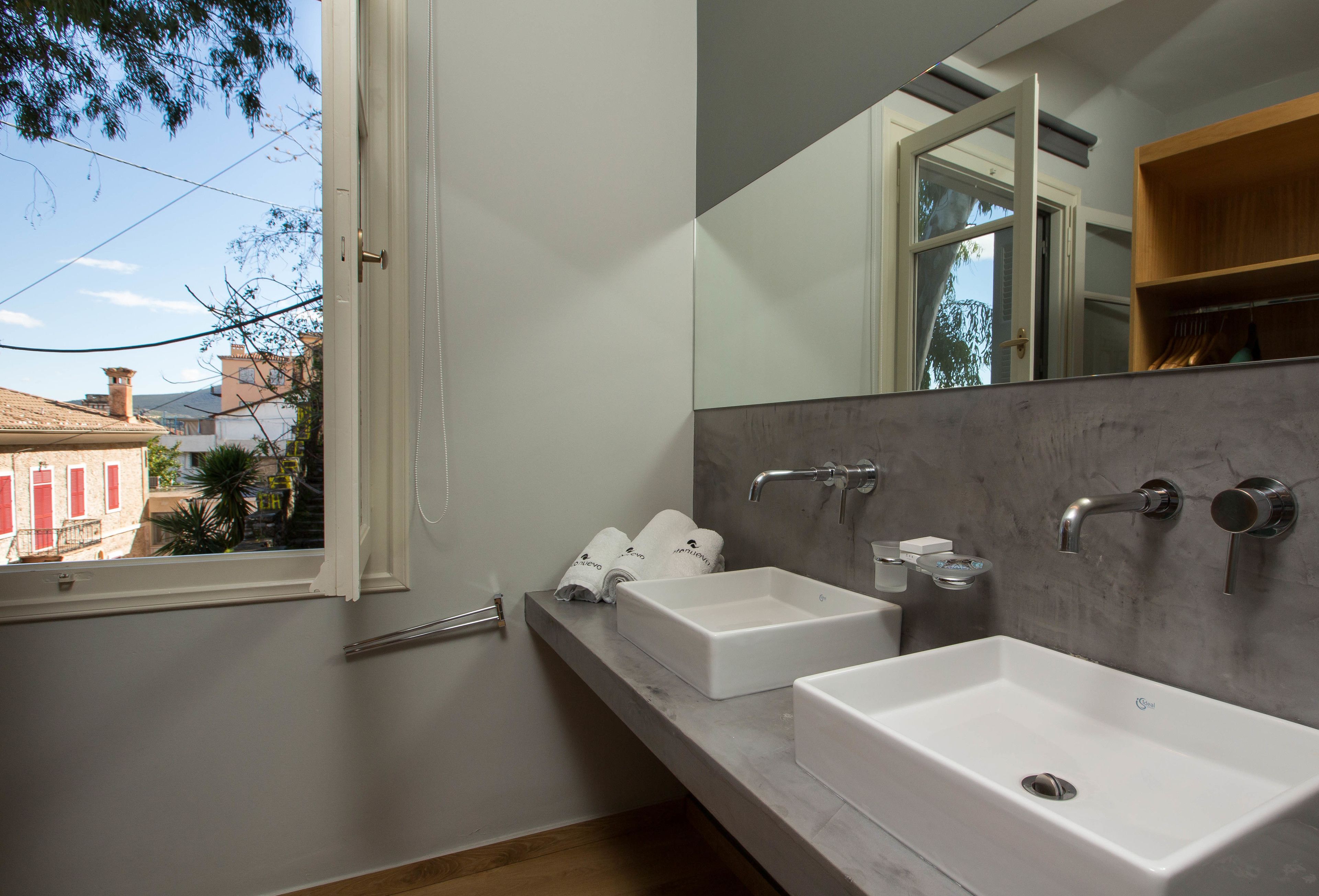 A bathroom with two white sinks, a large mirror, and a window.