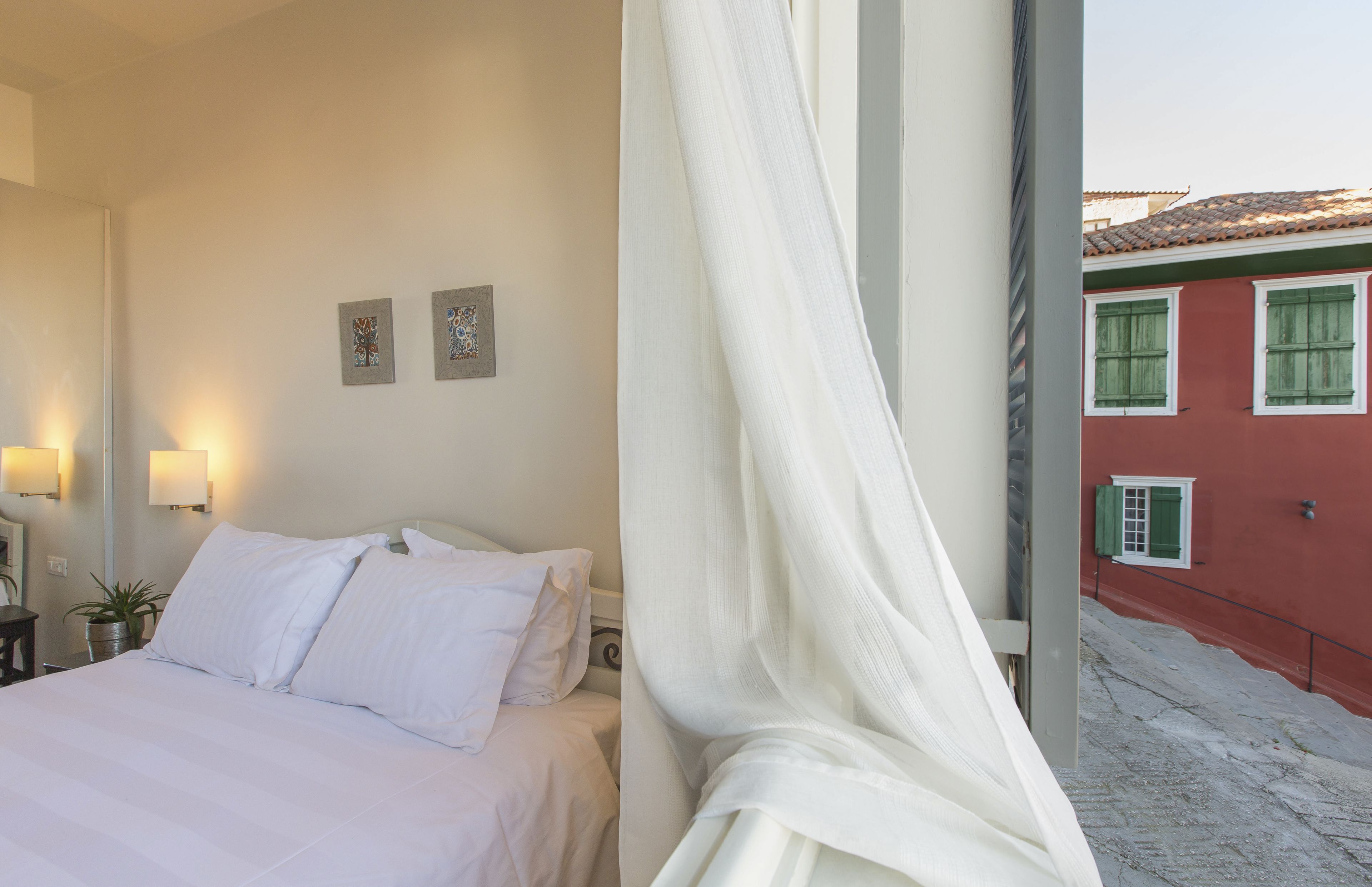 A hotel room with a bed, two wall-mounted lamps, and two framed pictures.