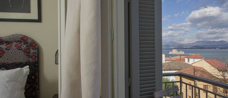 A balcony with a view of a coastal town and mountains.