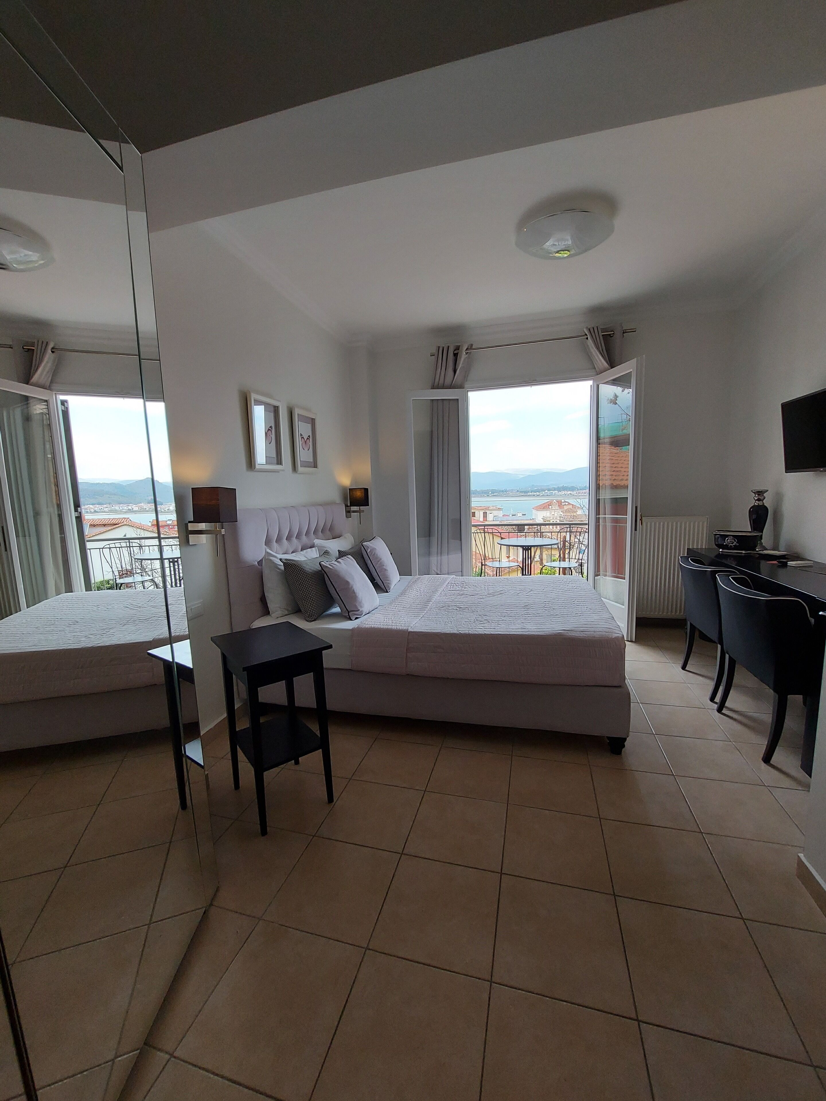Ein modernes Schlafzimmer mit einem großen Bett, einem Schreibtisch und Blick auf die Stadt.