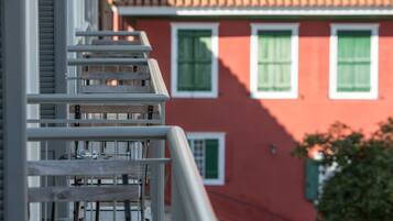 Un bâtiment rouge avec des volets verts et une balustrade de balcon blanche.