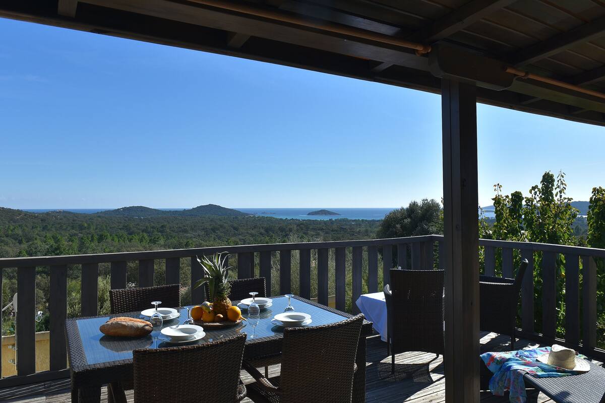 A deck with a table set for two, overlooking a scenic landscape.