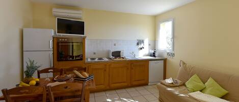 A compact kitchen with a dining table, chairs, a refrigerator, a microwave, and a built-in oven.