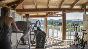 A covered outdoor gym area with exercise equipment, including treadmills and stationary bikes, overlooking a scenic landscape. - Résidence Chiar' Di Luna (Zonza)