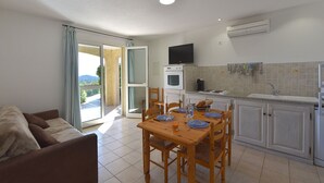 A compact living space with a dining area, kitchenette, and a sofa. - Résidence Chiar' Di Luna (Zonza)