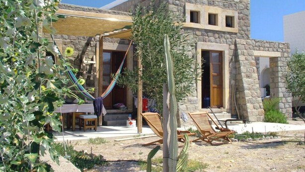 A stone building with a covered patio, outdoor seating, and a hammock. - Villa Patmos Netia (Patmos)