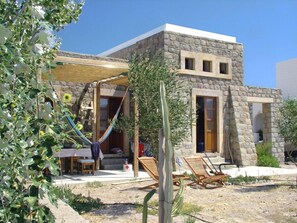 A stone building with a covered patio, outdoor seating, and a hammock. - Villa Patmos Netia (Patmos)