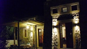 A stone building with a covered patio area featuring a table and chairs. - Villa Patmos Netia (Patmos)