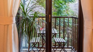 A balcony with a potted plant, wooden furniture, and a view of greenery outside. - HappyGuests Apartments (Kraków)