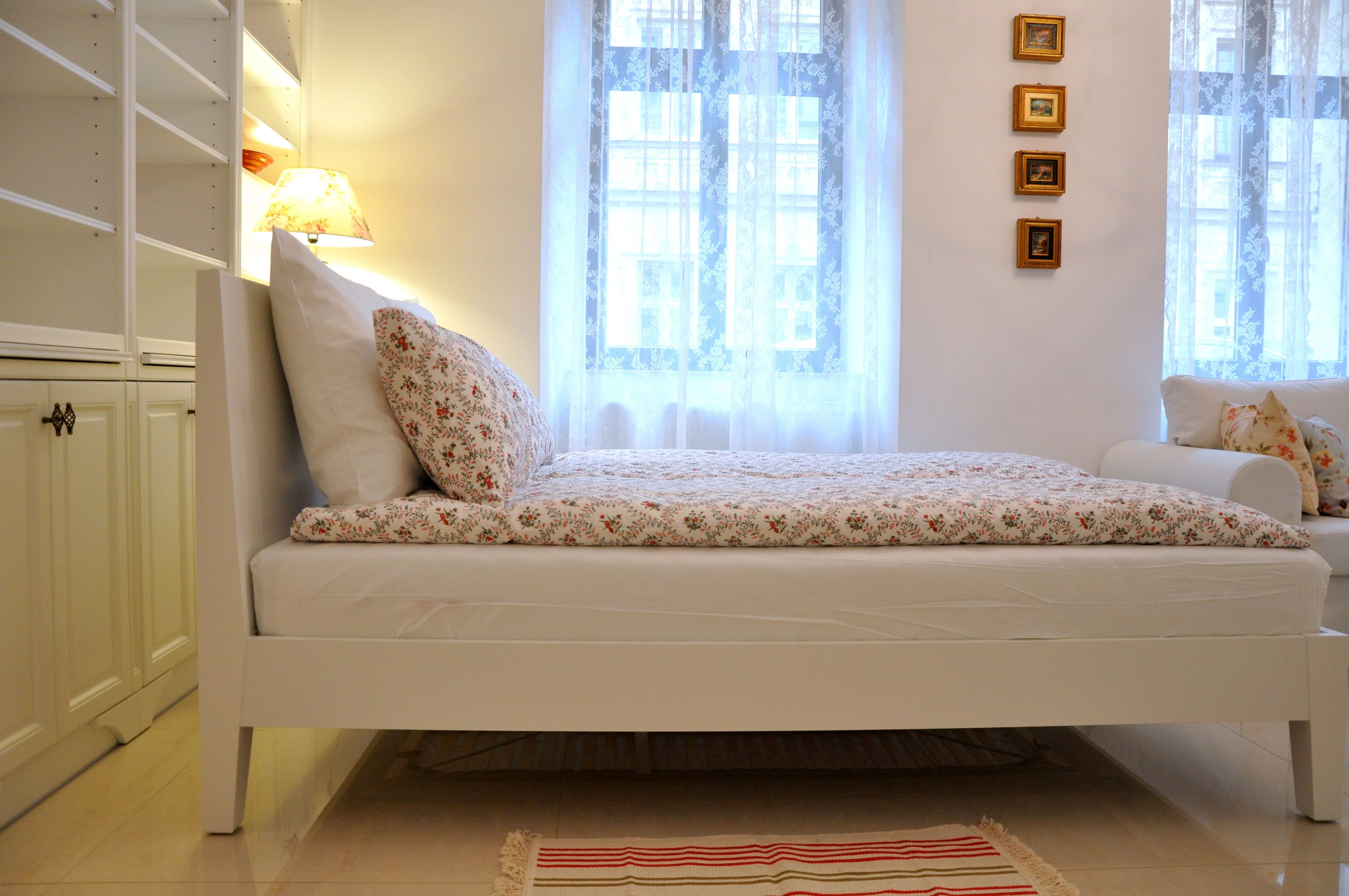 A bedroom with a bed, a nightstand, a lamp, and a window with curtains.
