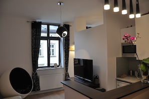 A modern kitchen with a flat-screen TV, a dining area with a round table, and a window with curtains. - HappyGuests Apartments (Kraków)