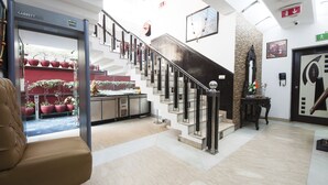 A hotel lobby with a marble floor, a staircase with metal railings, a reception desk, and potted plants. - Golden Leaf (New Delhi)