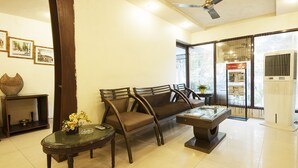 A living room with a sofa, two armchairs, a coffee table, and a decorative vase. - Golden Leaf (New Delhi)