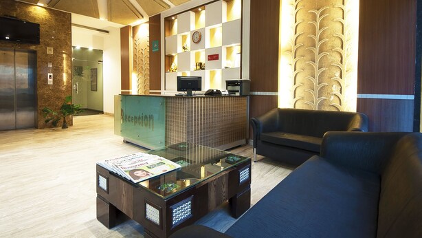 A reception area with a reception desk, a sofa, a coffee table, and a TV mounted on the wall. - Golden Leaf (New Delhi)