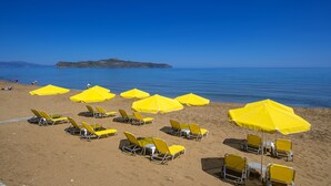 A beach with yellow umbrellas and sun loungers. - Sea Side Apartments (Chania)