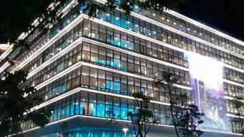 A multi-story building with a modern architectural design, featuring a prominent glass facade and a series of illuminated windows.