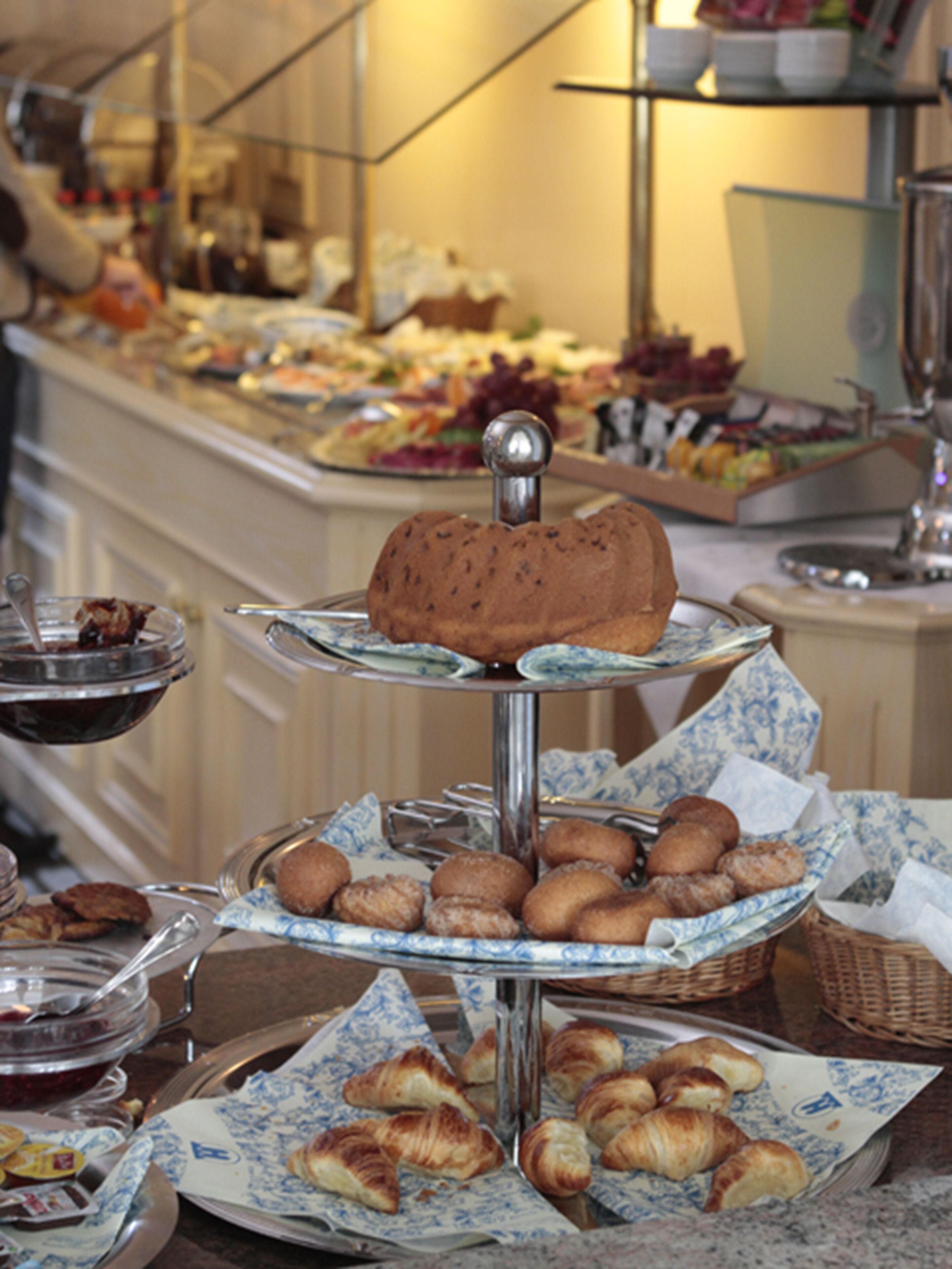 A buffet with various food items including pastries and a cake on a multi-tiered stand.