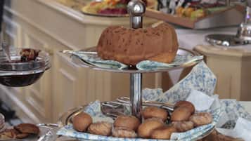 A buffet with various food items including pastries and a cake on a multi-tiered stand.