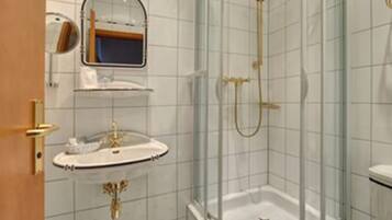 A bathroom with a sink, mirror, and shower.