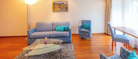 A modern living room with a sofa, armchair, and glass coffee table.