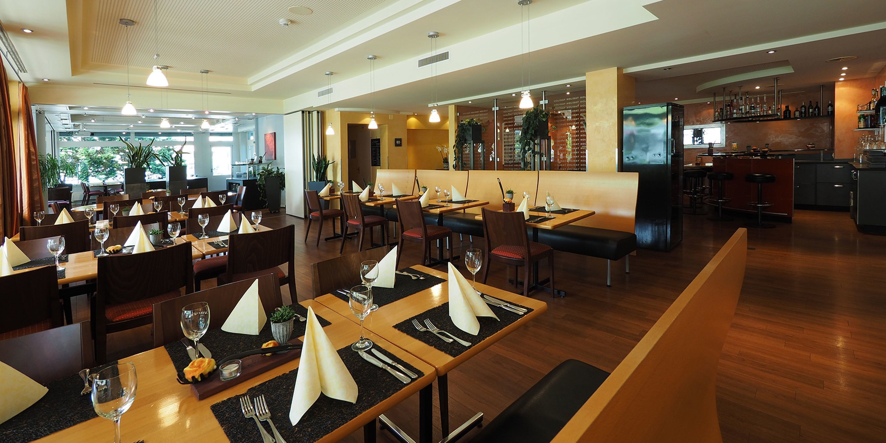 Um restaurante com várias mesas, cadeiras e um balcão.