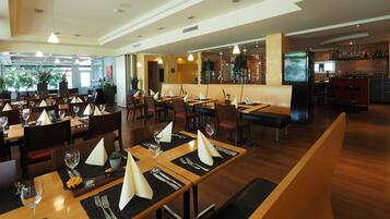 A restaurant with multiple dining tables, chairs, and a bar area.