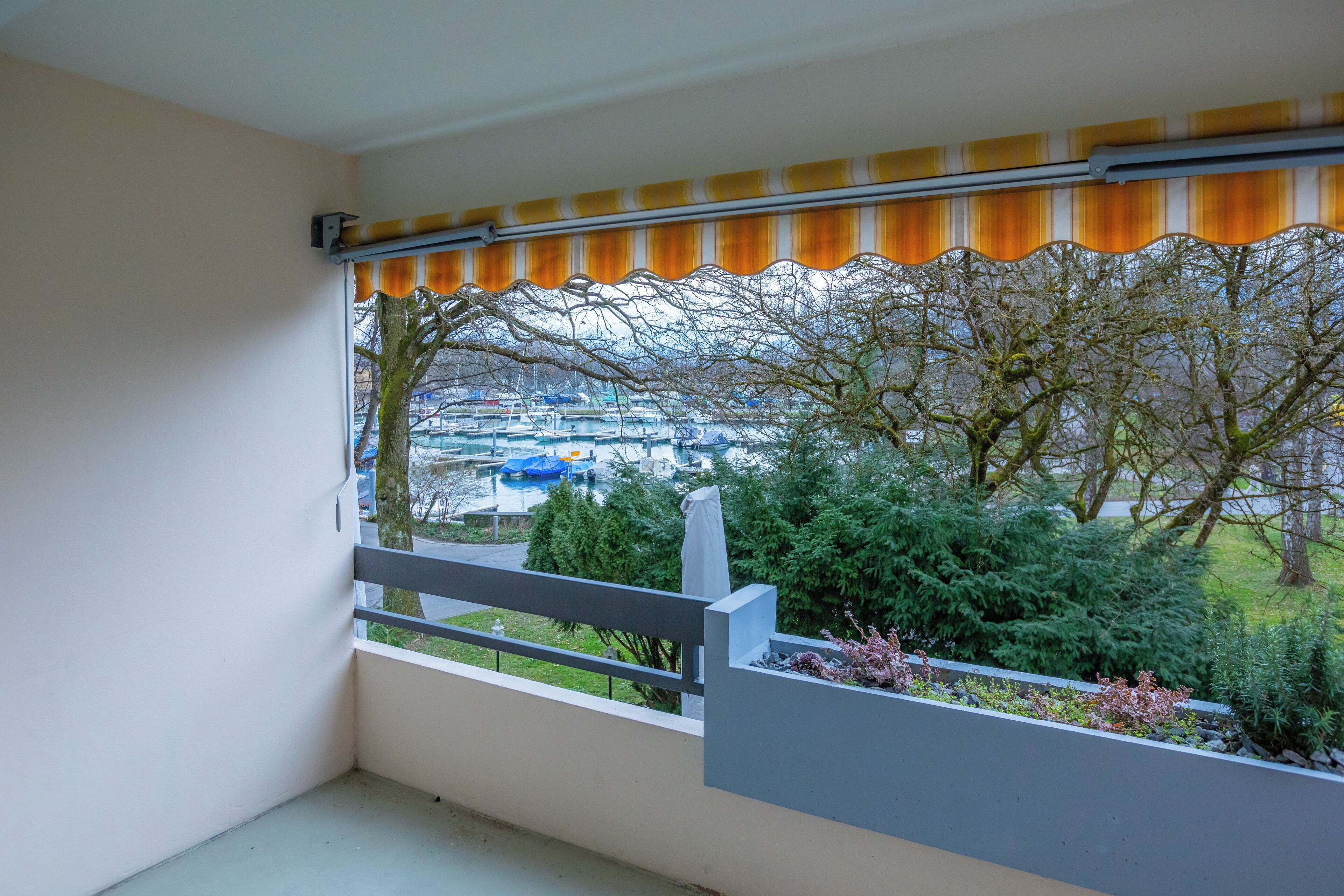 Een balkon met uitzicht op een parkeerplaats en bomen.