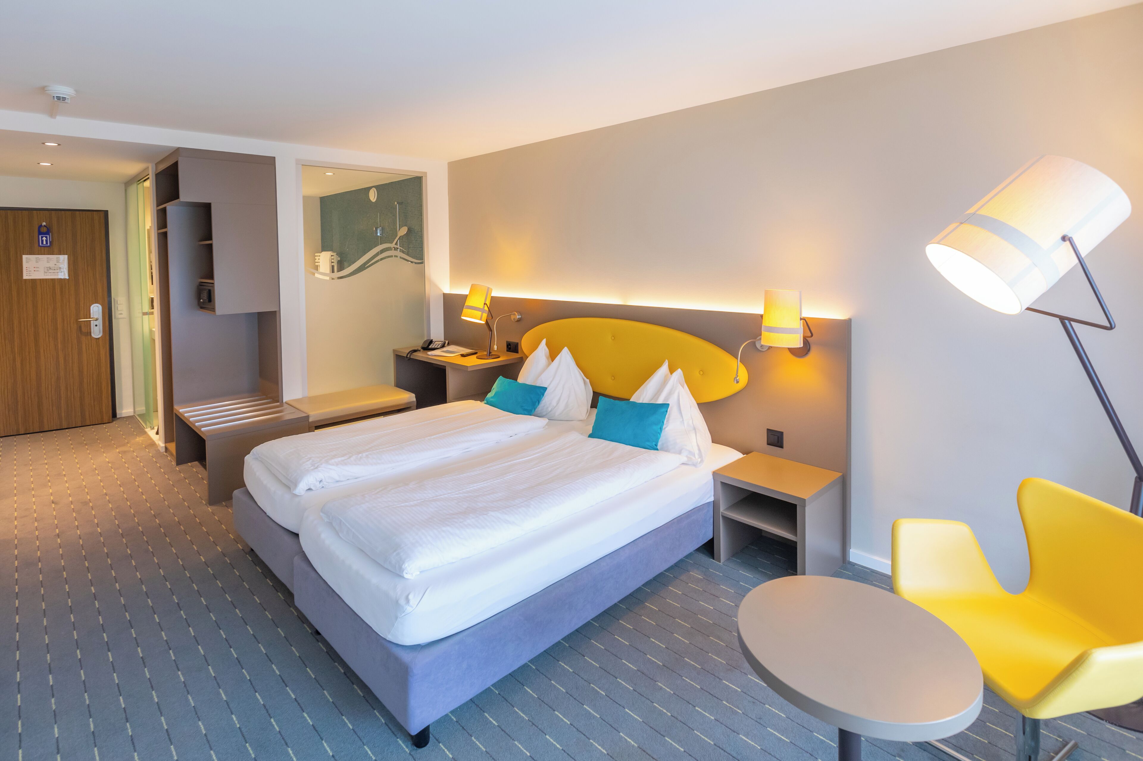 A hotel room with a large bed, bedside tables, a chair, and a desk.