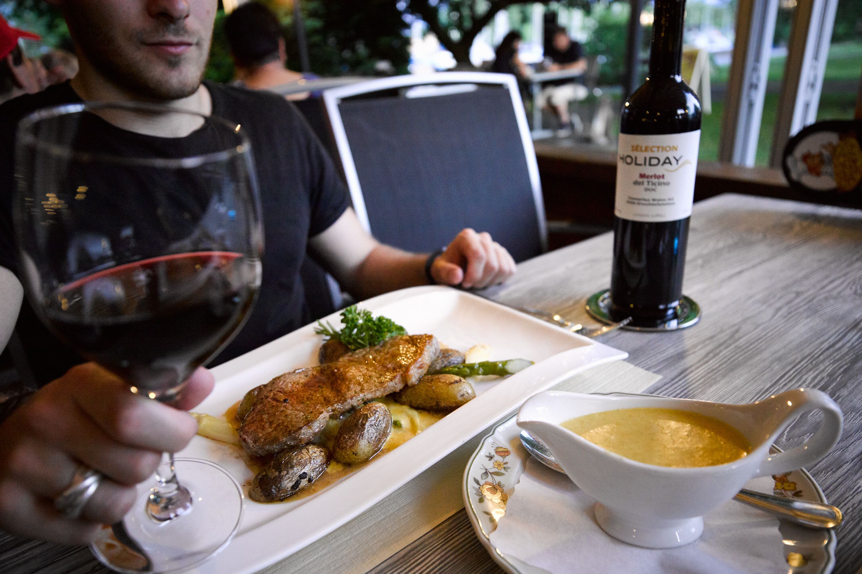 Una mesa de comedor con un plato de comida, una botella de vino y una coctelera.
