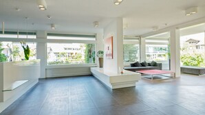 Un hall d’entrée spacieux comprenant un comptoir d’accueil, un espace salon et de grandes fenêtres donnant sur l’extérieur.