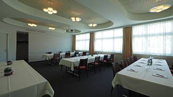 A conference room with multiple tables, chairs, and a projector screen.