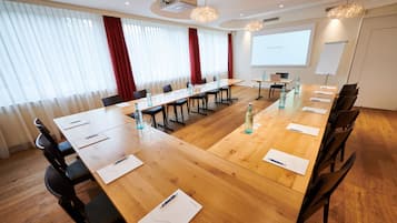 A conference room with a long wooden table, black chairs, and a projector screen displaying "HOLIDAY".