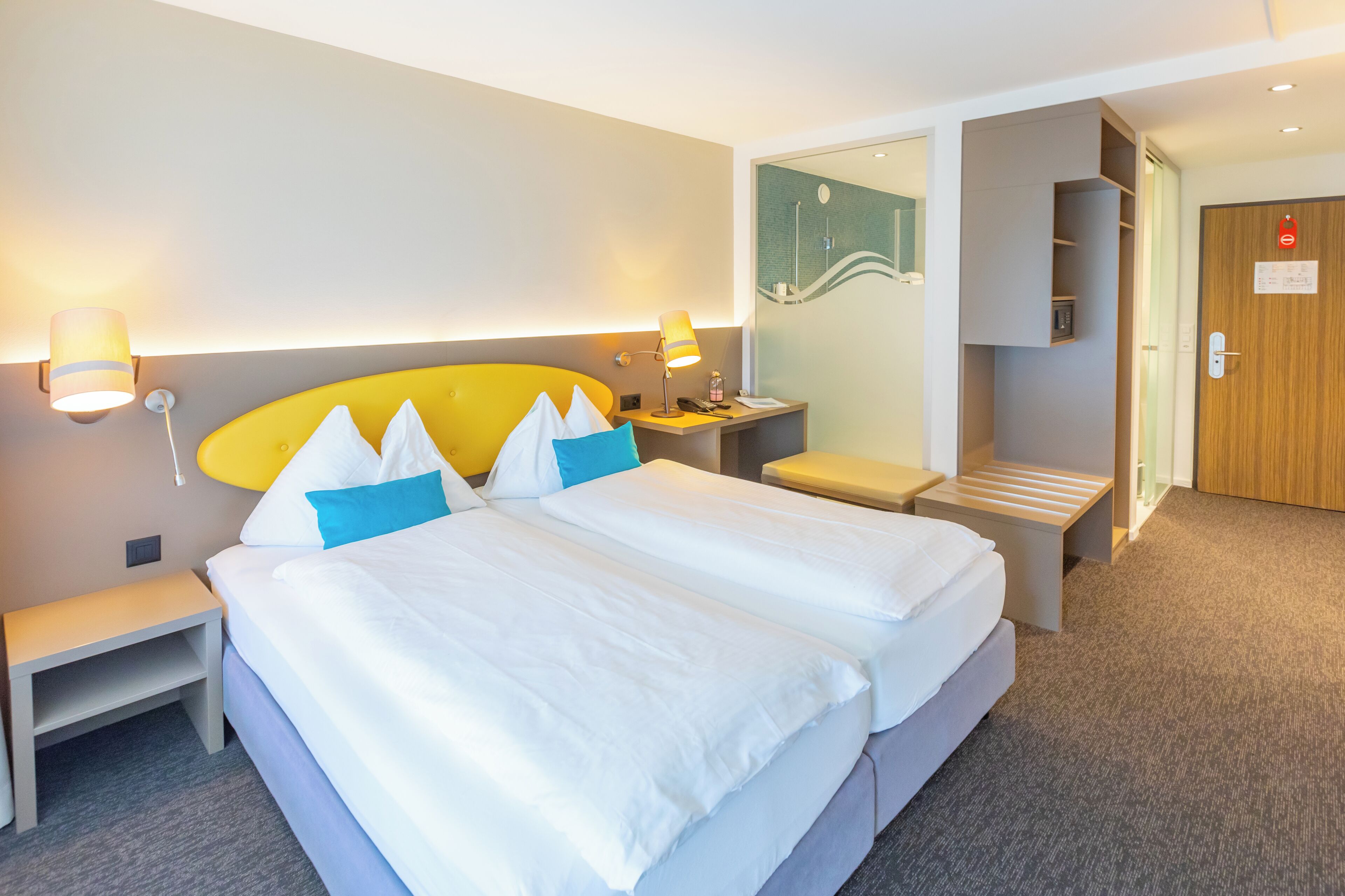 Ein Hotelzimmer mit einem großen Bett, Nachttischen, einem Schreibtisch und einem Kleiderschrank.