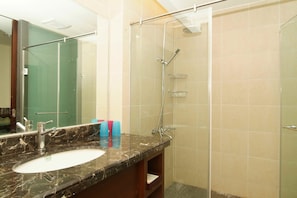 A bathroom with a glass-enclosed shower, a marble sink, and a mirror. - Xitou Education Center Hostel (Lugu)