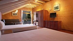 A bedroom with a sloped ceiling, wooden walls, a bed, a desk, and a television. - Haoshengdi (Lugu)