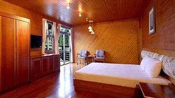 A wooden room with a bed, a TV, and a chair.
