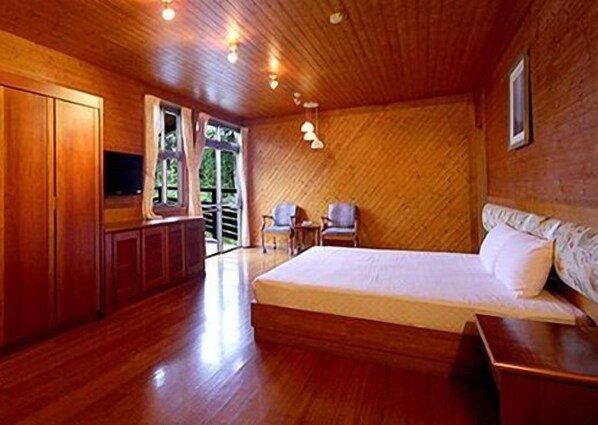 Una habitación de madera con una cama, un televisor y una silla.