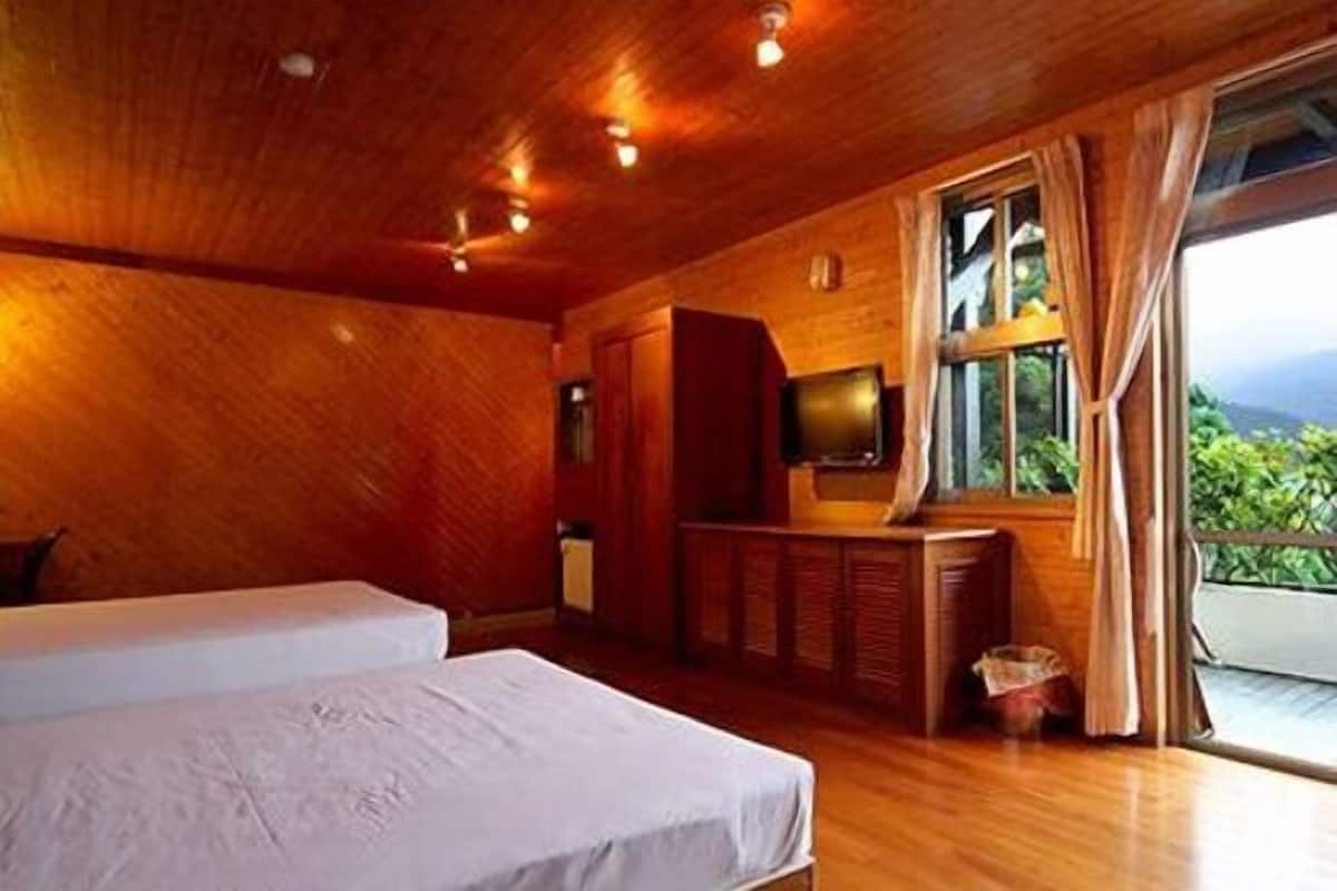 A wooden room with a bed, a television, and a window with curtains.