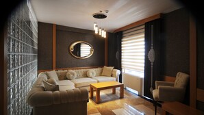 Una sala de estar moderna con un sofá, una mesa de centro y una silla. Hay un espejo grande en la pared y una lámpara decorativa colgante.