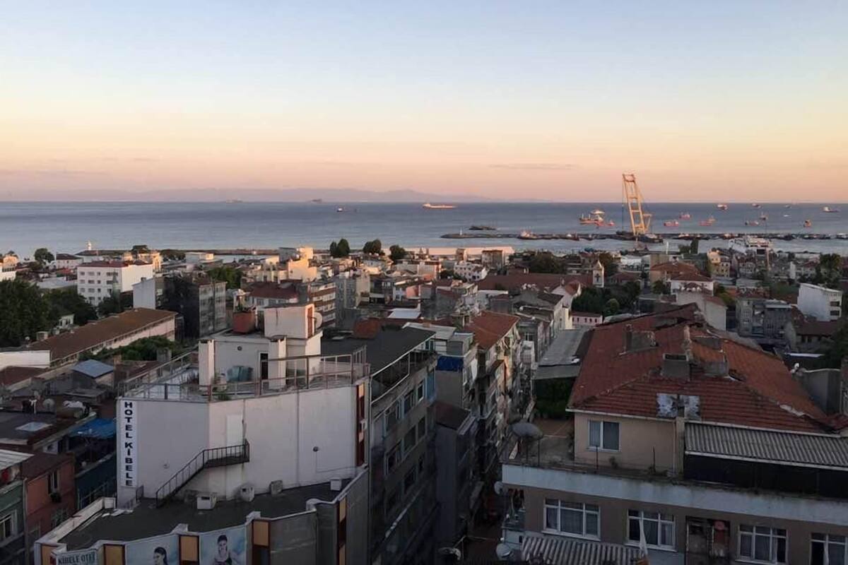 Un paisaje urbano costero con un hotel destacado llamado 'HOTEL KIBELE' y vista al mar con barcos.
