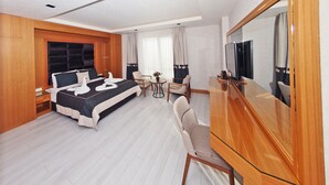 Una habitación de hotel moderna con una cama grande, televisión, escritorio y una silla.